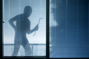 Burglar wearing a balaclava looking through the house window